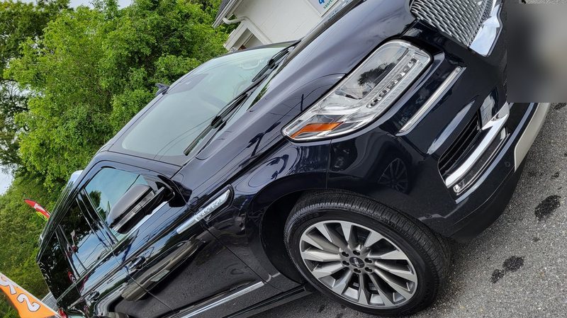 Freshly detailed black SUV with deep gloss parked outside the shop